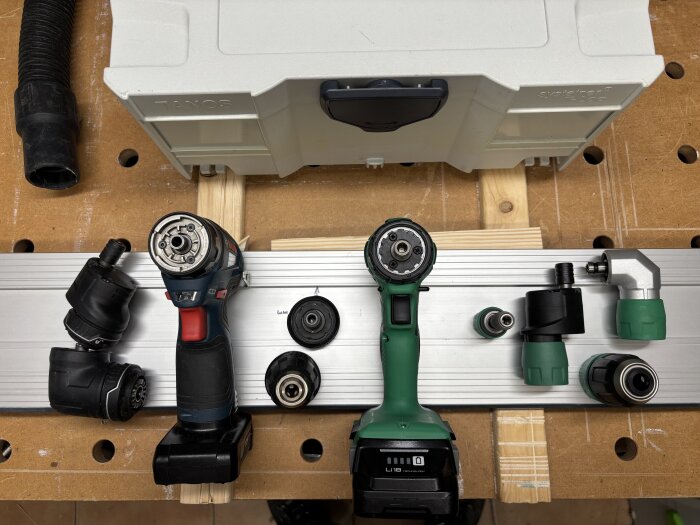 Två borrmaskiner sida vid sida med olika chuckar och tillbehör på ett arbetsbord, en Bosch och en grön Hikoki.