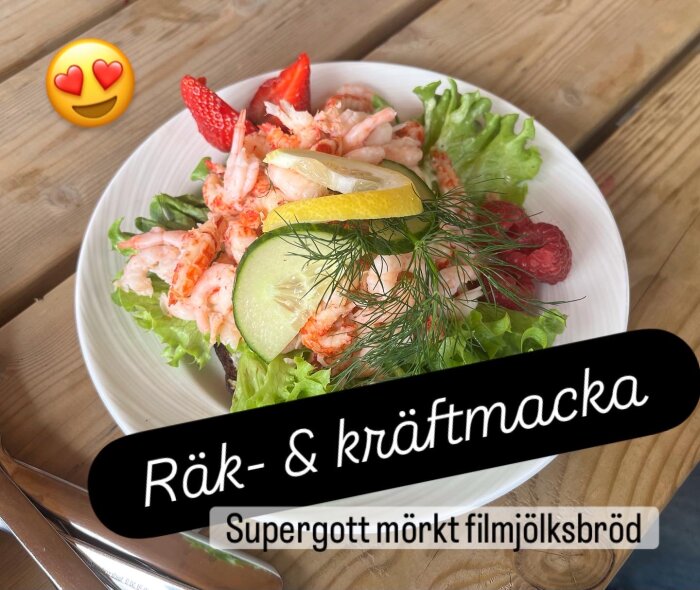 Räkmacka med kräftor på filmjölksbröd med sallad, gurka, citron och dill, serverad på tallrik. Jordgubbar och hallon som dekoration.