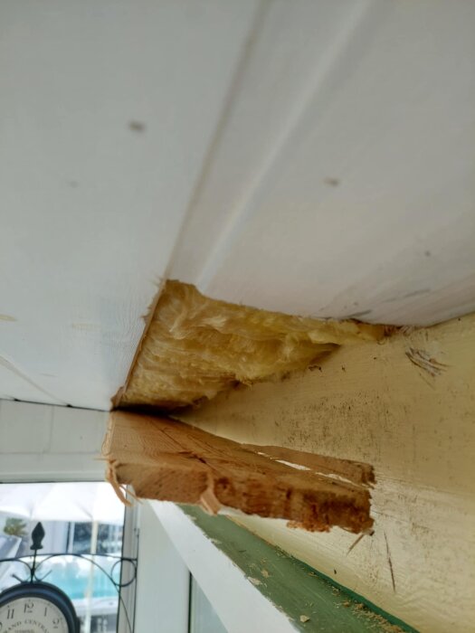 Förfallet altantak med blottad isolering och skadat trämaterial, visar skador som ska repareras i samband med renovering.
