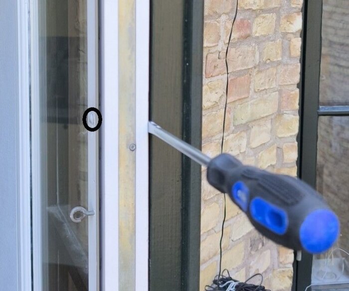 Skruvmejsel används för att lossa koppelskruvarna på ett fönster.