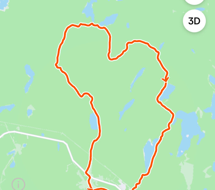 Karta visar en orange slinga liknande en cykel- eller vandringsrunda i ett grönskande område med sjöar, sedd uppifrån.