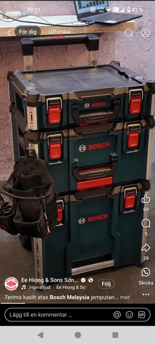 En stapel med tre Bosch L-BOXX-förvaringslådor med en verktygsbälte hängande på sidan.