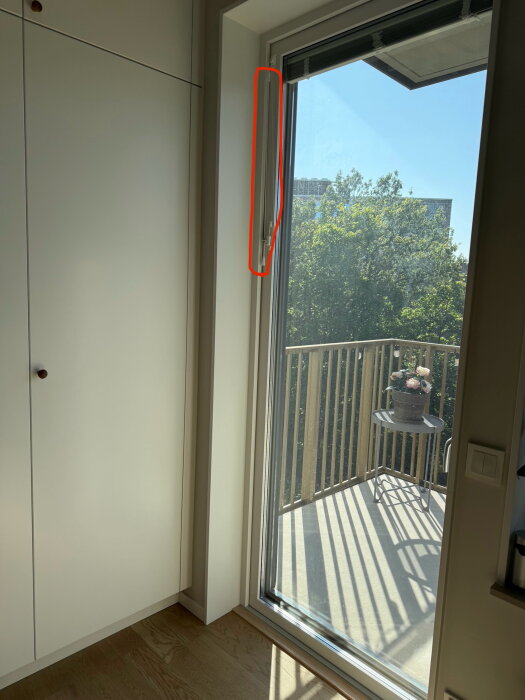 Balkongdörr med markerat område där ljud och luft släpps in vid gångjärnssidan, mot en bakgrund av uteplats och träd i dagsljus.