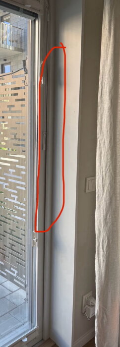 Balkongdörr med markerad röd linje som visar området där ljud och luft läcker in, synlig tätning och utsikt över uteplatsen.