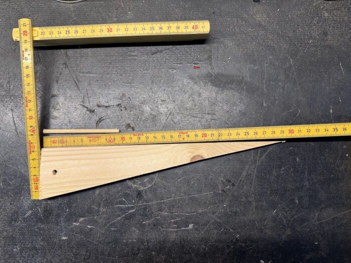 Träkil för markduk med måttband på en arbetsyta.