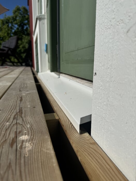 Terassi, jossa näkyy puinen kynnys ja oven tiivistelevy; kysymys liittyen trallin asennukseen kynnyksen kohdalla.