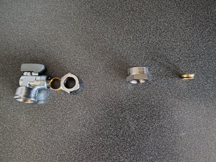 Delar för VVS-installation på bord: kulventil med mutter och stödhylsa, en gängad adapter och en planadaptern eller bussning.