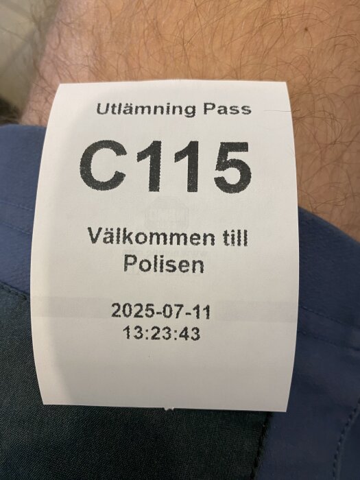 Kölapp för passutlämning hos polisen med nummer C115, datum 2025-07-11 och tid 13:23:43, placerad mot en blå bakgrund.