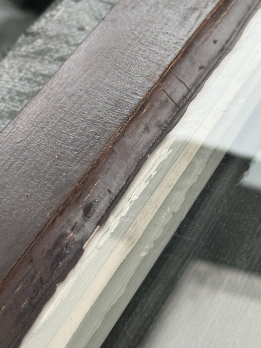Fönsterkarm med avskavd färg och slitet kitt, redo för renovering och målning.