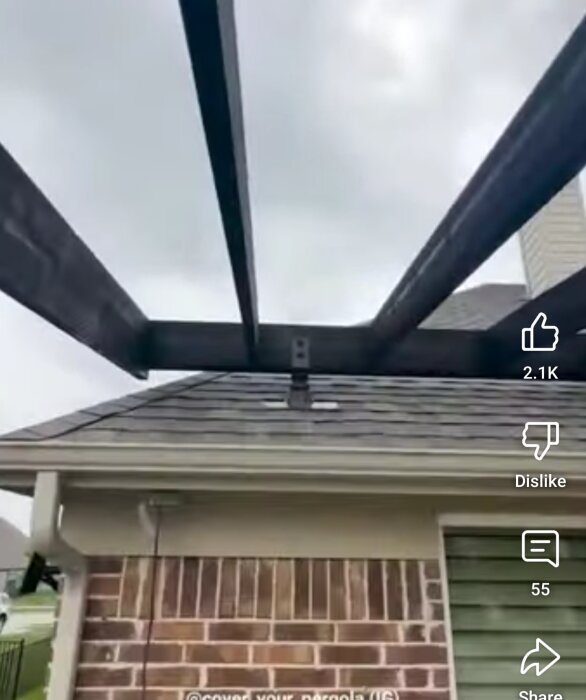 En pågående byggnation av en pergola med takstolar över en tegelbyggnad under en molnig himmel.