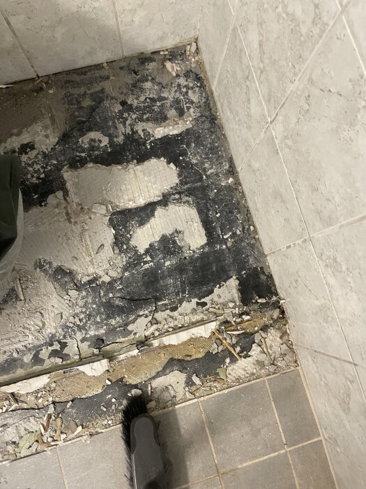 Underlag för klinkergolv i badrum med synligt spackel och avfall, fråga om golvskikt före klinkerläggning.