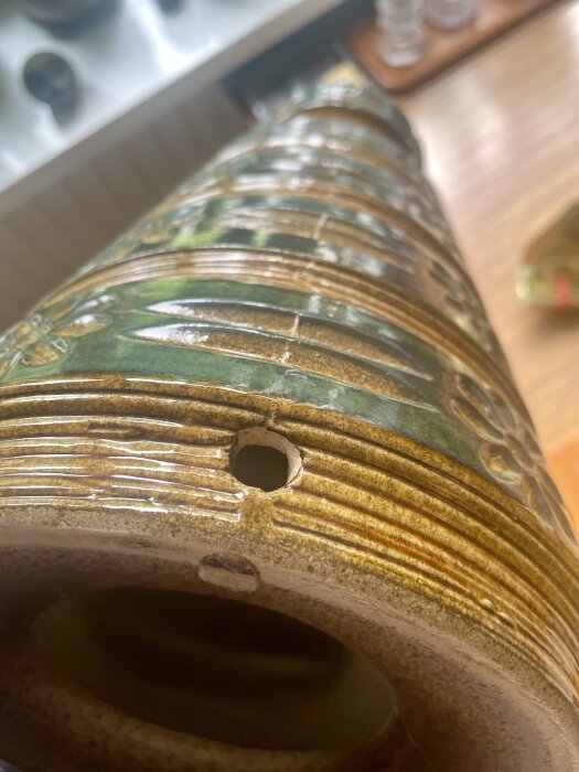 Keramisk lampfot med hål för kabeldragning, grön och brun med mönster.