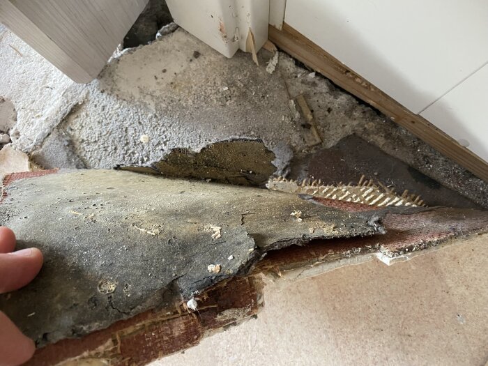 Gammal golvmatta underifrån, delvis uppbruten, visar lager av slitage och spår av installation i en byggnad från 1958.