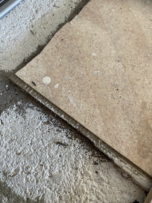 Linoleumgolv på väv med svart underlag, delvis avlägsnat för att visa lagerstrukturen och underlaget i ett renoveringsprojekt.