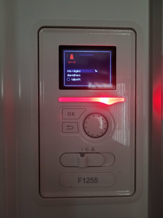 Närbild av en bergvärmepump med display som visar pressostatlarm 58.