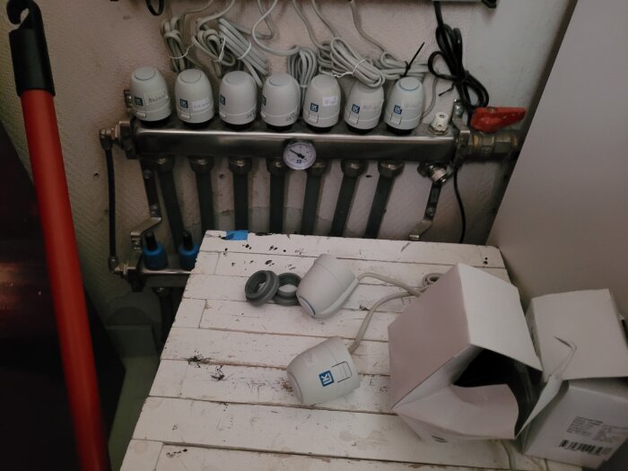 Ställdon installerade på en rörkoppling med en mätare, flera nya ställdon syns bredvid i sina förpackningar.