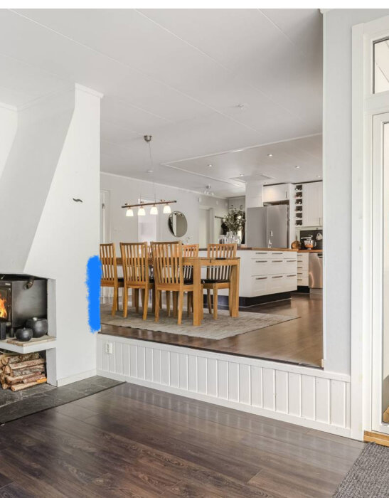 Interiörbild av hus med eldstad, nivåskillnad mellan vardagsrum och kök/matplats. Två trappsteg och markerat område för eventuell babygrind.