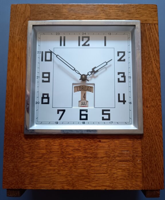 Klassisk sparur från 1920-30-talet med träkabinett, visartavla och datumvisning av "Lördag 4 Juli".