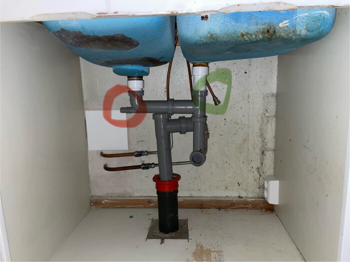 Diskbänkens undersida med VVS-rör, röda och gröna cirklar markerar platser för diskmaskinens avlopp och vattentillförsel.