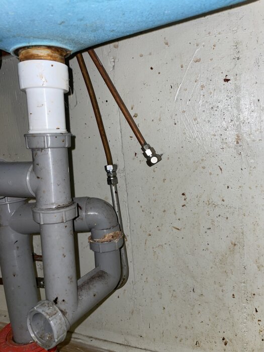 Bild under diskbänk visar VVS-installation med avloppsrör och två kopparrör. Röd ring markerar avloppsplats, grön ring för vattenanslutning till diskmaskin.