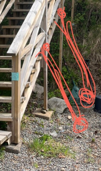 Trätrappa med vingliga stöd och röda markeringar, föreslagen förstärkning genom att gjuta plintar. Trädgårdsverktyg i bakgrunden.