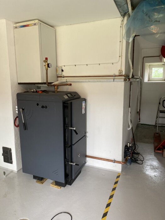 Panna med ny rördragning på en vit vägg i en källare.