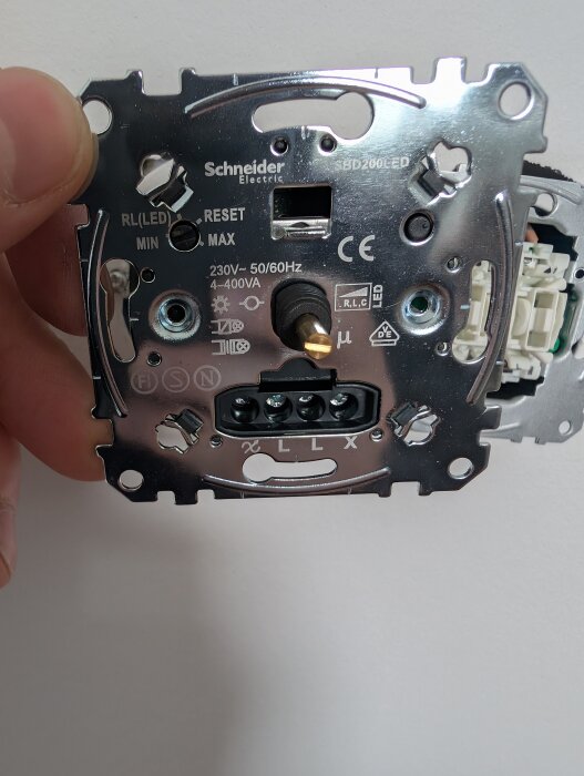 Dimmer från Schneider Electric med inställningar och märkningar, hållen i en hand.