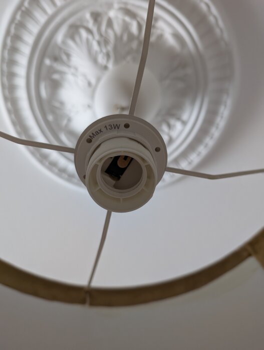 Tom lamphållare med text "Max 13W" och dekorerat tak i bakgrunden.