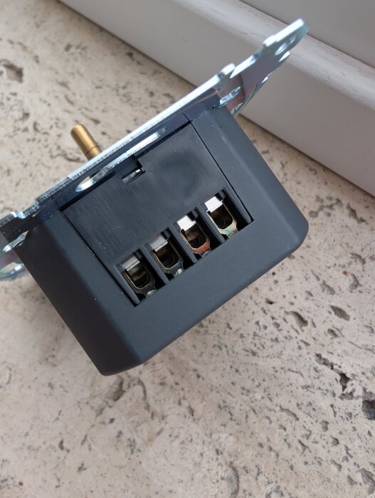 Elektrisk komponent med synliga terminaler, potentiellt felkopplad, som ligger på golvet.