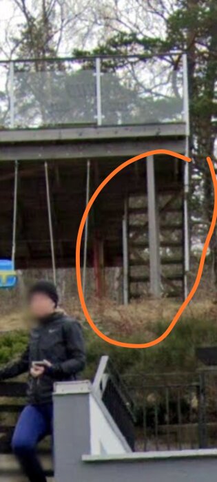 Underifrån vy av en stabiliserad trappa med stödstrukturer, skogen i bakgrunden och en person på en trappa i förgrunden.