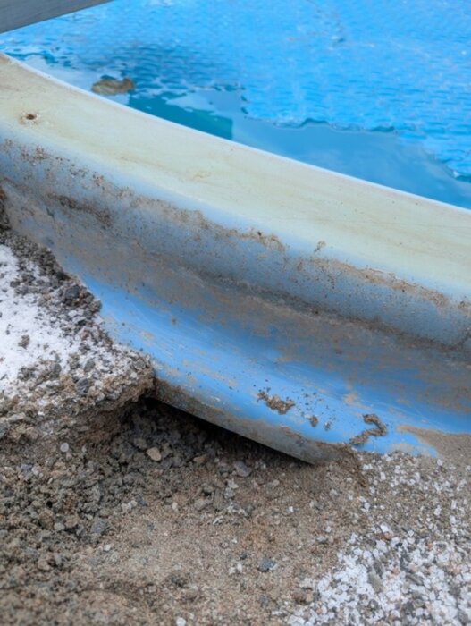 Nära bild på poolkant av glasfiber med synlig sand och jord. Kan prevalenta som möjligt kapningsområde enligt diskussionen om pooldäckbygge.