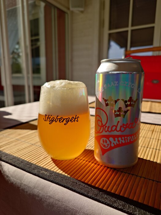 En glas öl från Stigbergets bredvid en glänsande ölburk med texten Budvar på ett bord.