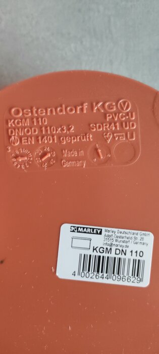 Orange rördel med märkningen "Ostendorf KG" och specifikationer, inkl. "KGM 110" och "Made in Germany", samt en etikett från Marley Deutschland GmbH.