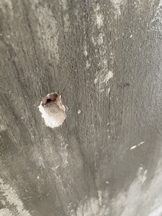 Kaminmurstock med gammal puts som delvis har lossnat, visar behovet av nytt putslag för renovering.