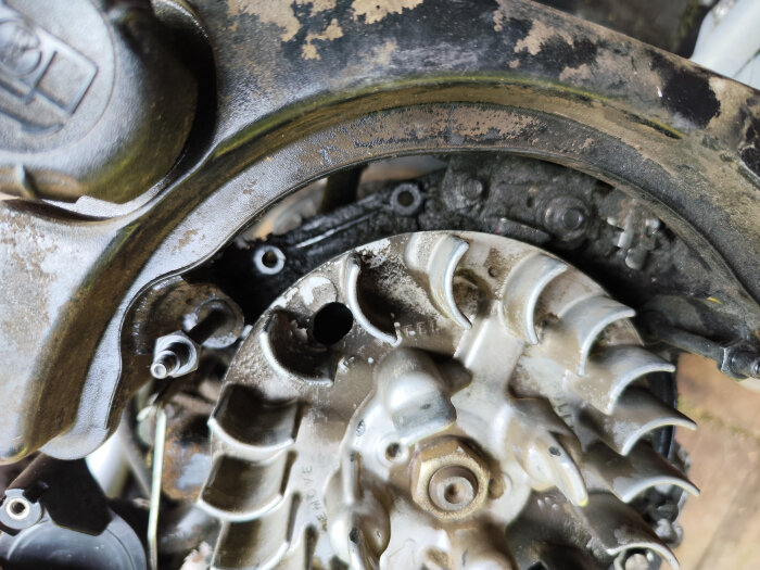 Närbild av en trasig växelströmsgenerator som lossnat ur sitt fäste i motorn på en Stiga Multiclipper.