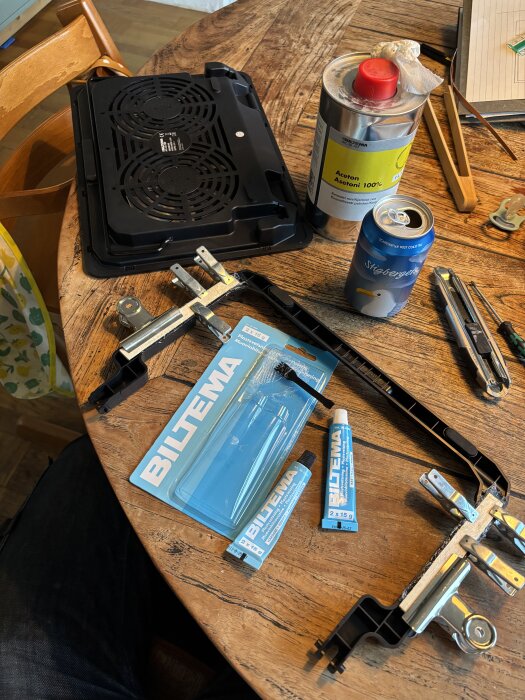 Biltema-produkter, inklusive klämmor, lim och lösningsmedel, laptopställ och Stigberget ölburk på ett träbord.