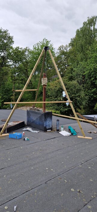 Stålskorsten omgiven av träställning på tak, förberedd för kapning med verktyg och material runt omkring.