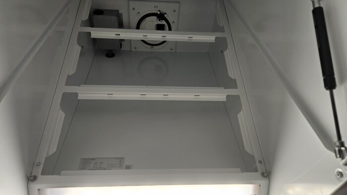 Öppen fläktkåpa utan fettfilter, visar insidan med två hyllor och ventilationsmekanism för att ge tilluft när fläkten är avstängd.