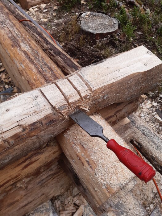 Runtimmer med huggjärn och snitt för rännknut, omgiven av träflis och sågspån.