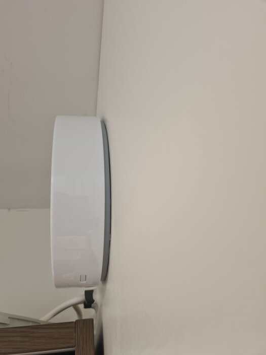 En vit fläkt monterad på en vägg med en synlig glipa mellan fläkten och väggen.