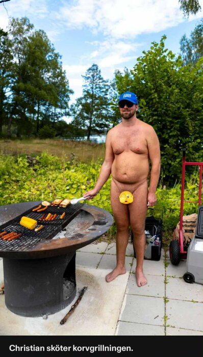 En person står vid en grill utomhus och grillar korv och majs under en klar himmel.