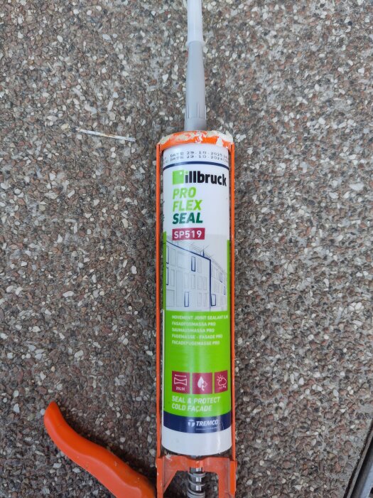 Patron med illbruck SP519 fogmassa placerad i en fogspruta, liggande på en grov betongyta.