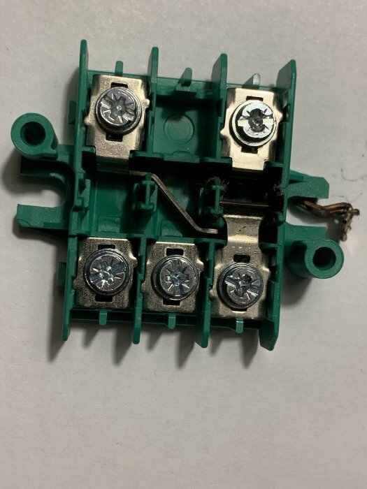Inre delen av en Eljo/Schneider trappströmbrytare med skruvkopplingar, monterad på en grön platta, synliga metallkomponenter.