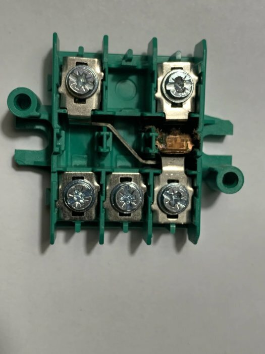 En isärplockad Eljo/Schneider trappströmbrytare med synliga skruv- och kabelanslutningar på en grön plastbas.