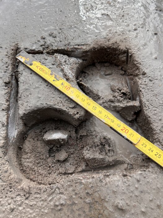 Hål i betonggolv med en tydlig mätningsskala bredvid för jämförelse.