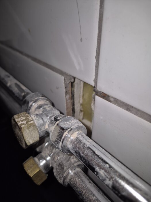 Rör och kakelvägg med synliga hål för eldragning och tätfrågor, enligt diskussion om byggplan och tätskikt.