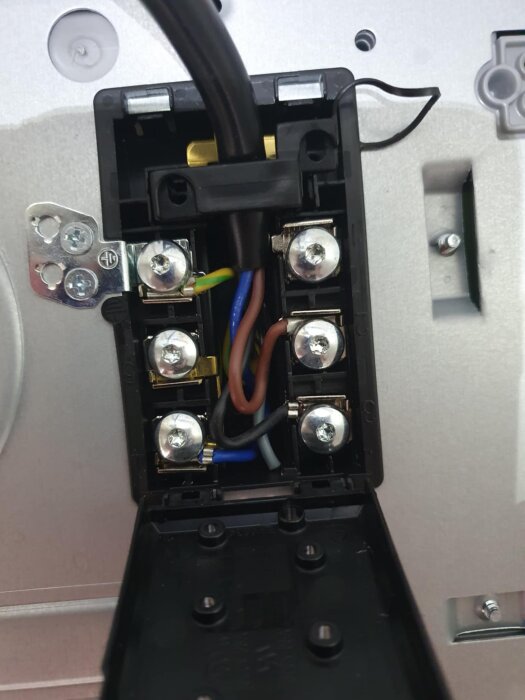 Anslutningsdosa med olika ledningar för induktionshäll, färger: gul-grön, brun, blå, grå och svart ledare kopplade till poler.