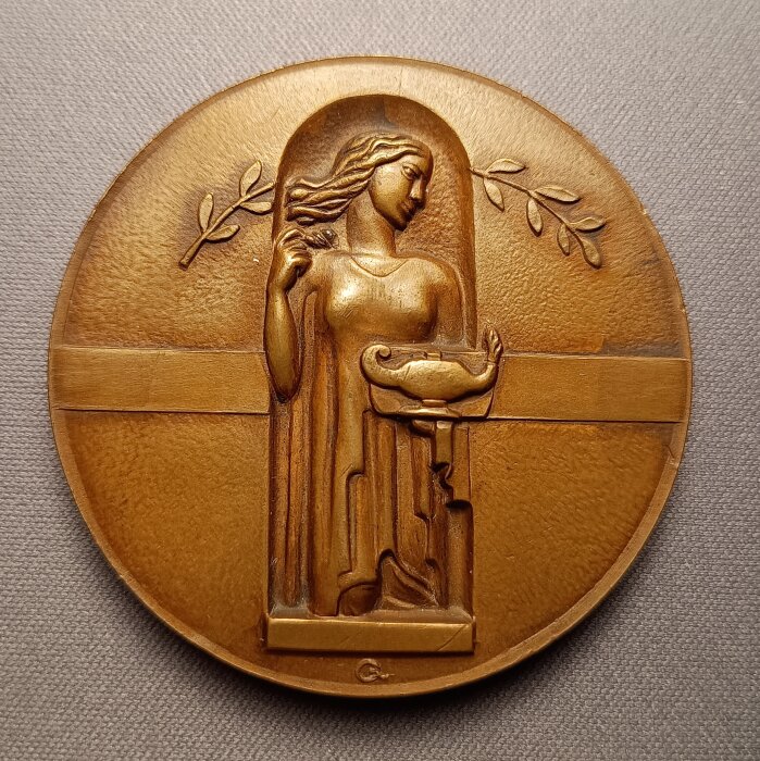 Minnesmedalj med relief av en kvinna som håller en kvist, tillägnad svenska familjer för att ha öppnat sina hem för finska krigsbarn under krigen.