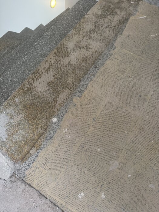 Slitna stentrappor med två typer av lim synliga på stegen, visar slitage och frågan handlar om asbestinnehåll.