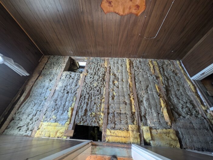 Golv med avlägsnat trägolv, visar skadad isolering och golvbrädor. Tecken på musaktivitet och ojämnt golv i rum 4x4m.